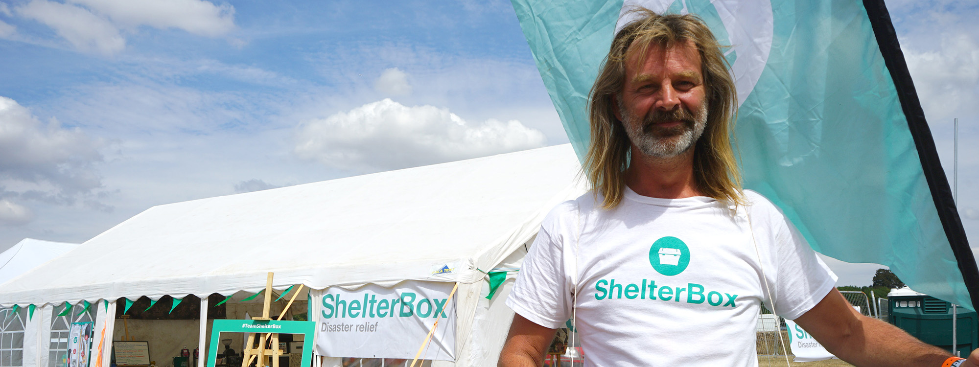 Man wearing ShelterBox t-shirt outside marquee