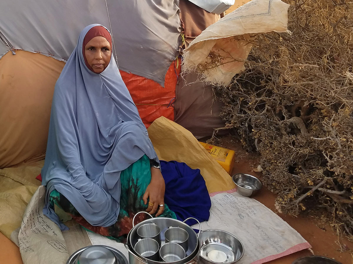 Woman sitting with kitchen items outside a tent in Somaliland