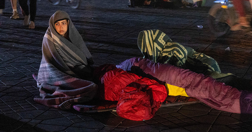 Woman sitting wrapped in scarf in street in Morocco after the earthquake there