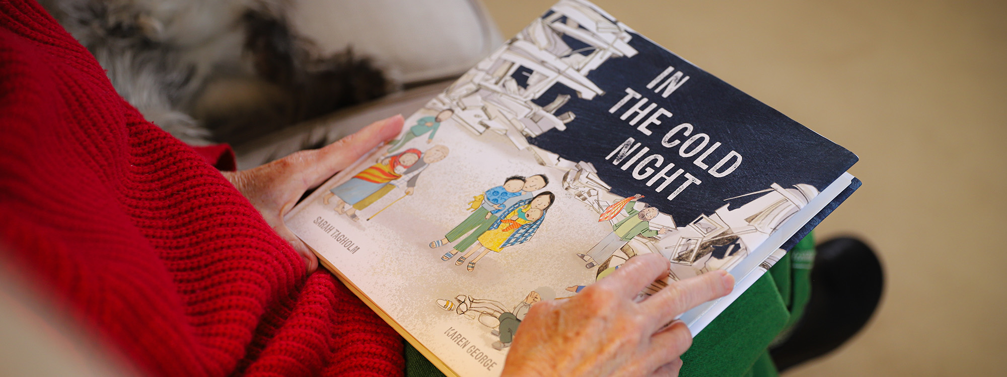 Book titled 'In the Cold Night' with illustrations by Karen George resting on someone's lap