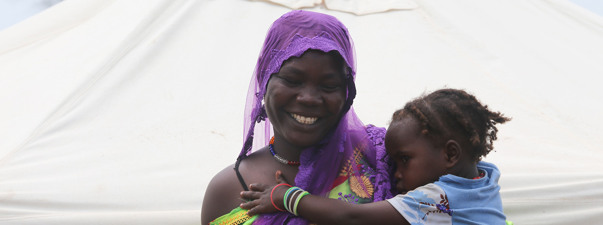 Woman holding a child in front of a tent in Chad