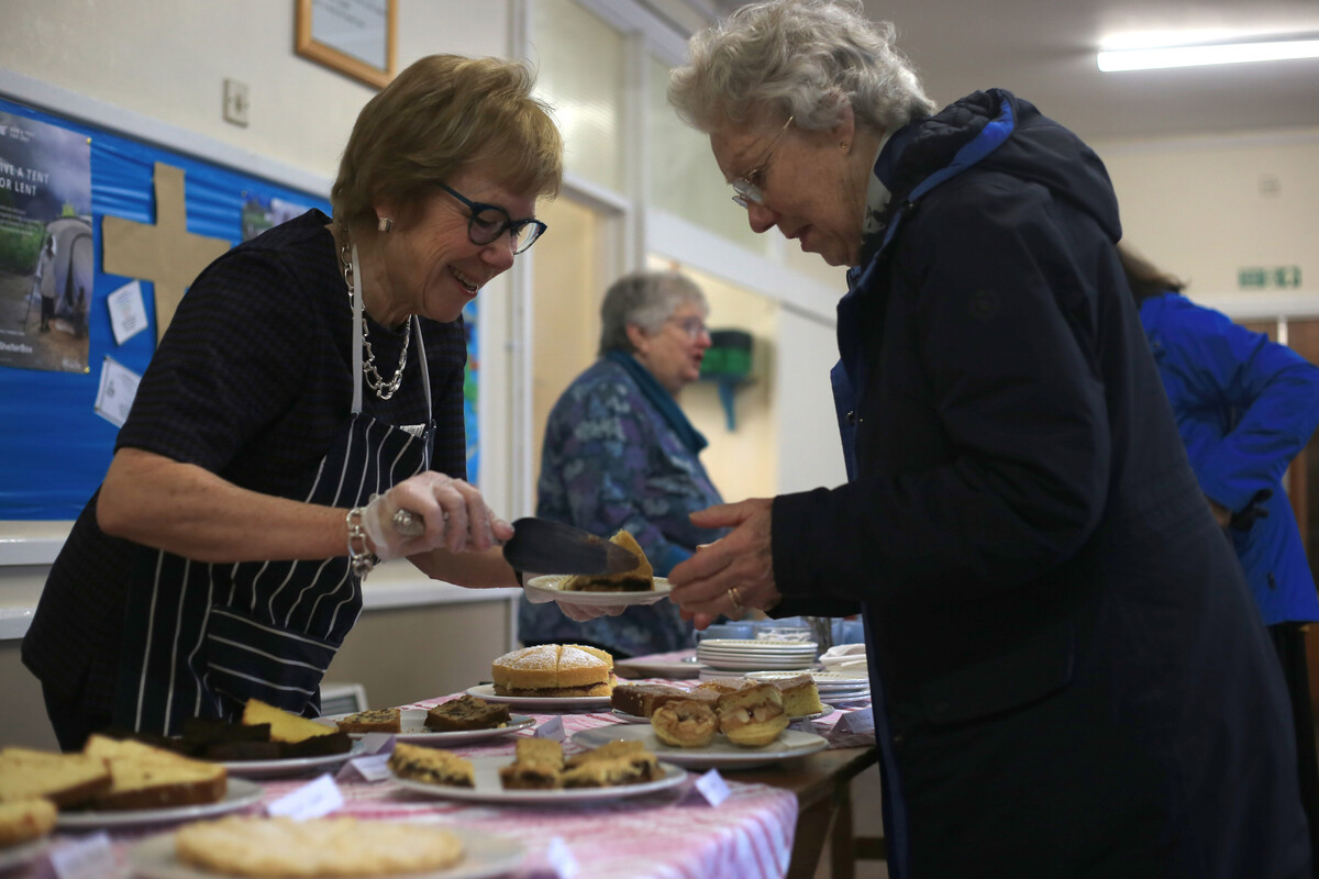 Someone serving someone else cake at a bake sale