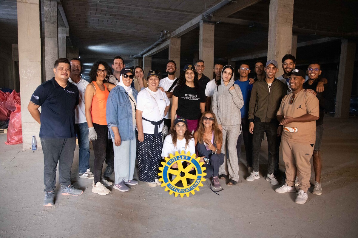Group of people in a warehouse in Morocco posing with a Rotary Logo