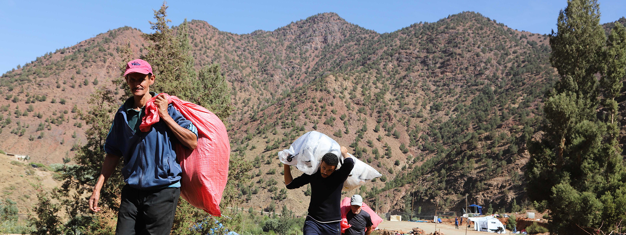People carrying bags of aid in the Atlas Mountains in Morocco