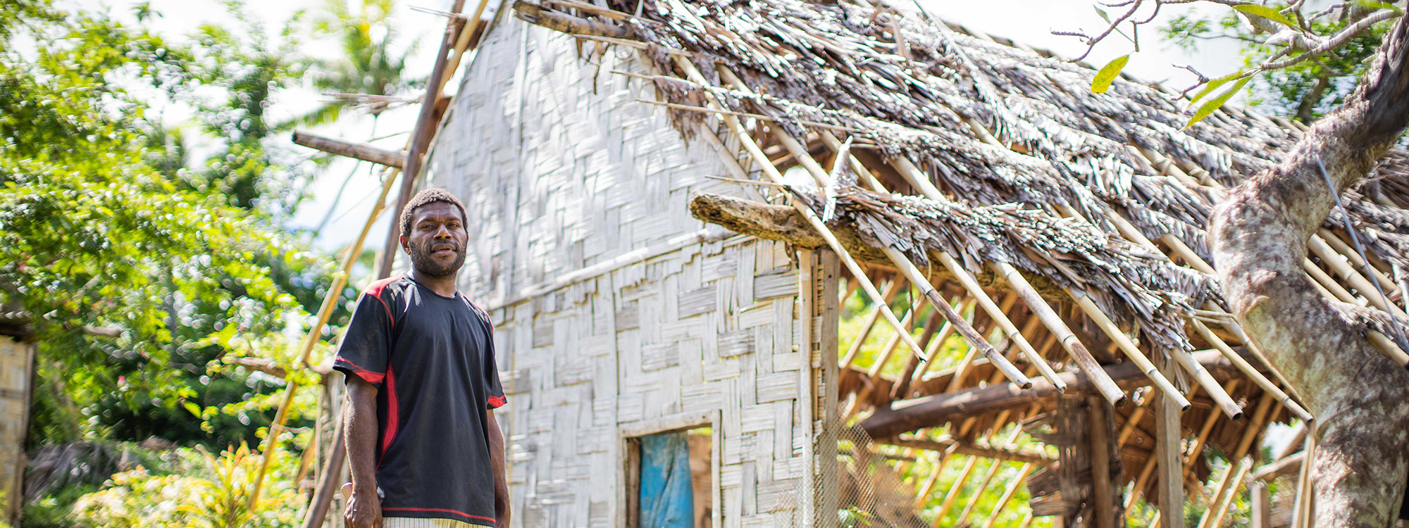 Man standing outside a building damaged by a cyclone in Vanuatu