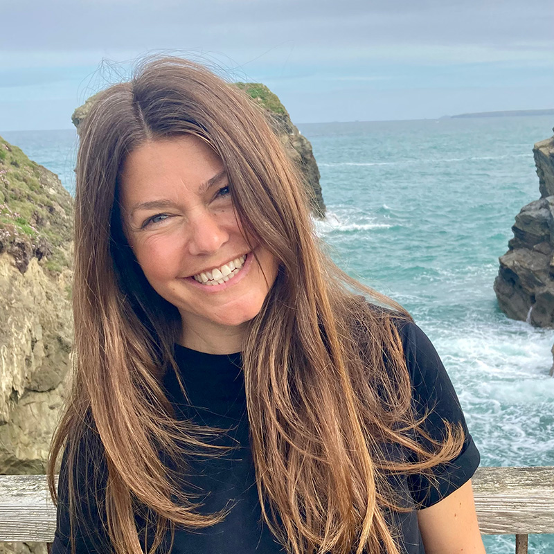 Photo of lady with long hair smiling in front of the sea
