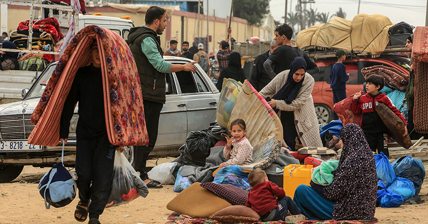 People sitting in the street and carrying their belongings after being forced from their homes in Gaza
