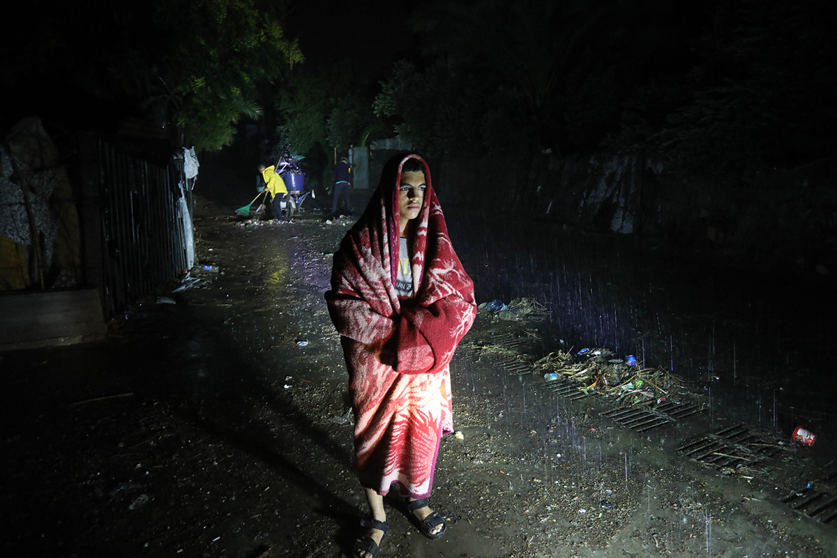 Man standing wrapped in a blanket in heavy rain in Libya caused by Storm Daniel