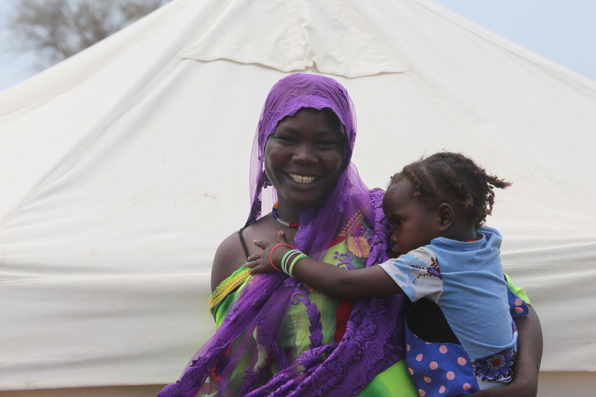 Woman holding her child outside a tent in Chad