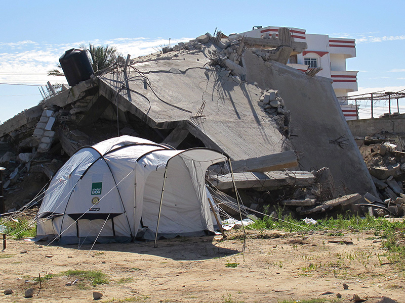 Destroyed building in Gaza with a ShelterBox tent outside of it from 2015