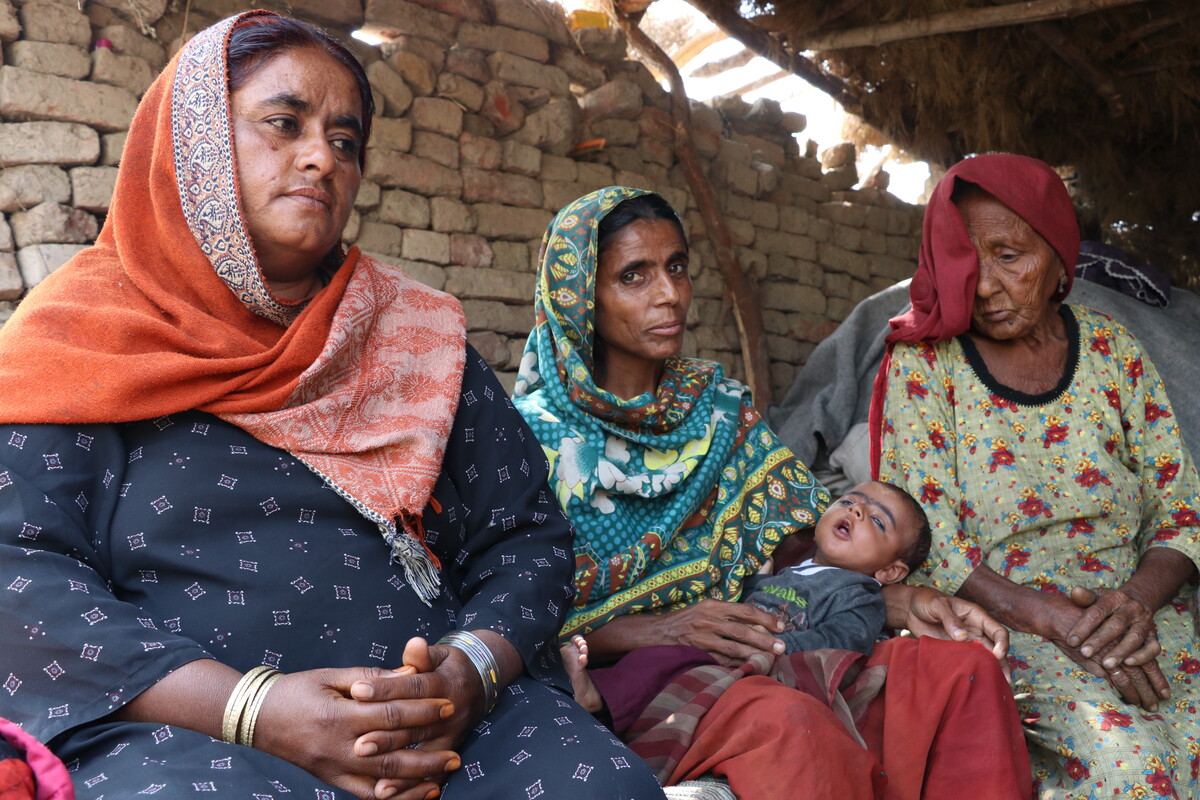 Three women, one with a baby on her lap, siting in a shelter in Pakistan