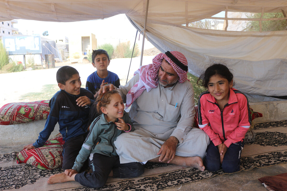 Man and three children sitting inside a tent in Syria