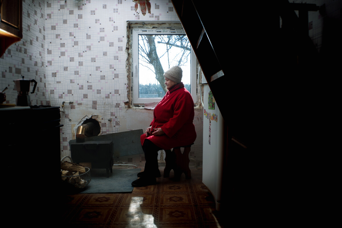 Woman sitting inside a damaged building with a stove in Ukraine
