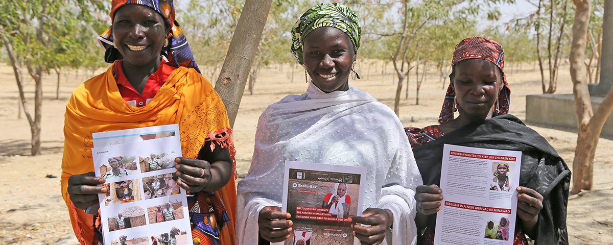 Three women in Cameroon holding publicity materials sharing their story