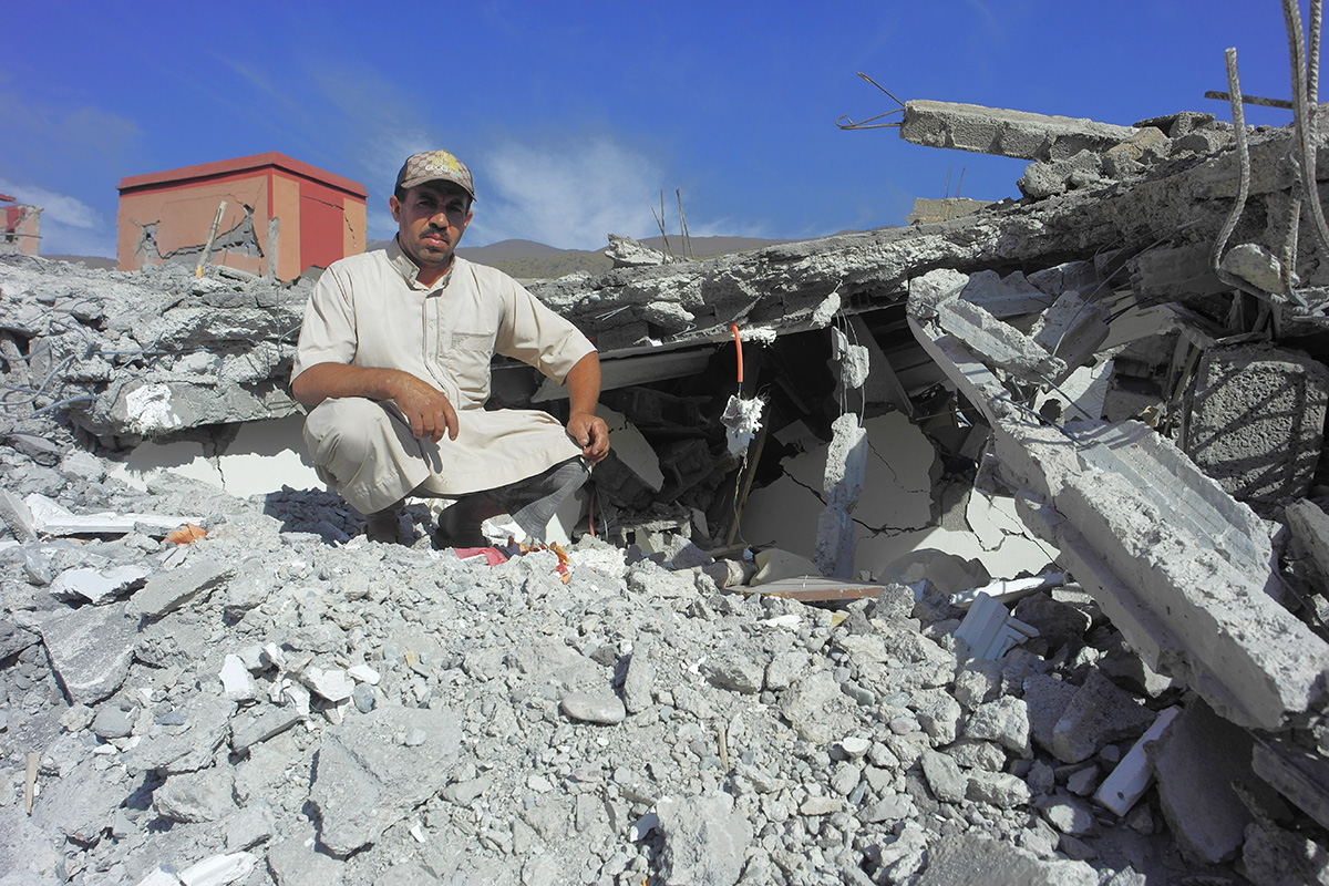 Man sitting on the rubble of a destroyed building in the Atlas Mountains in Morocco
