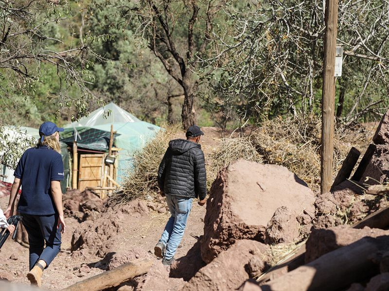 Two people walking through a damaged village in Morocco