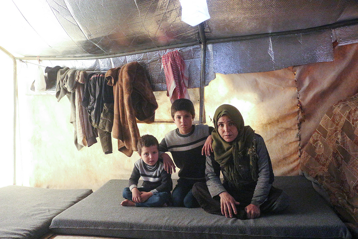 Woman and two children sitting inside a tent