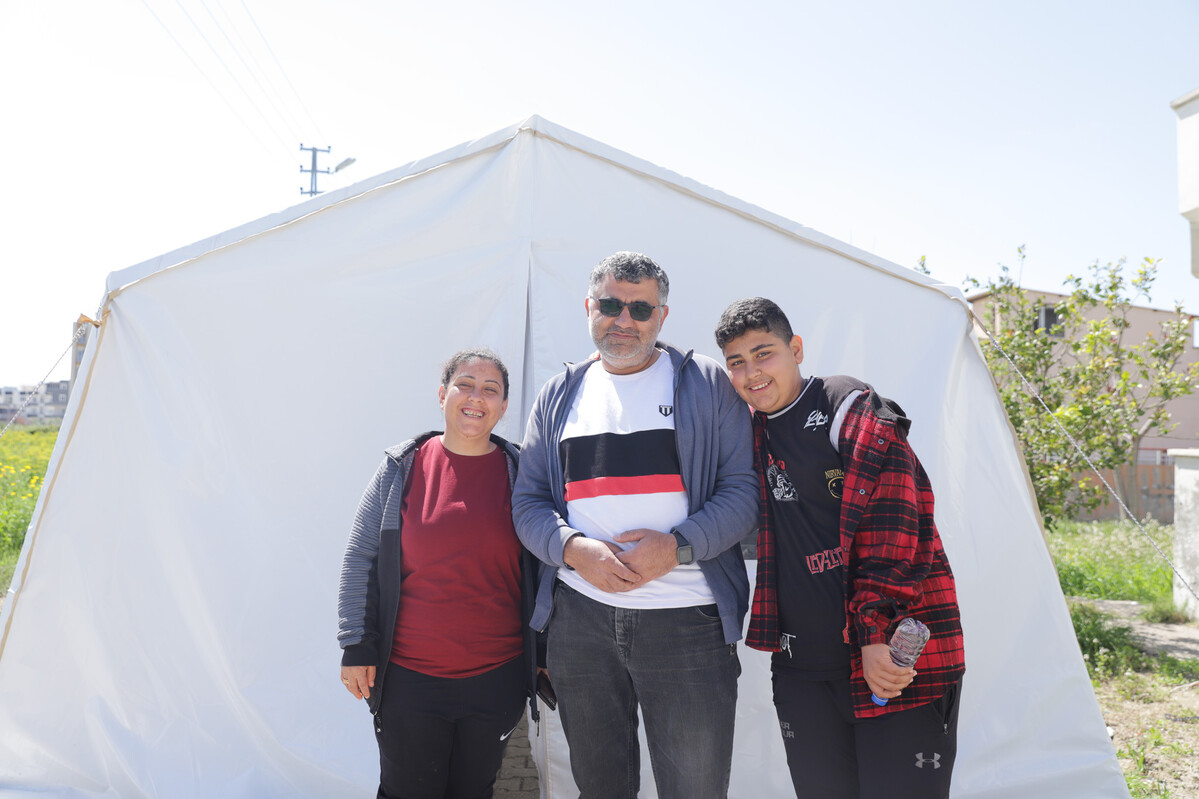 Three people standing in front of a tent after the earthquakes in Turkey