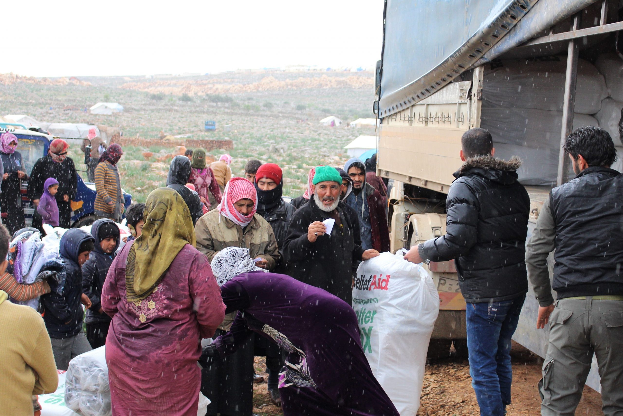 ShelterBix and ReliefAid aid being unloaded from a truck and handed to people in Syria
