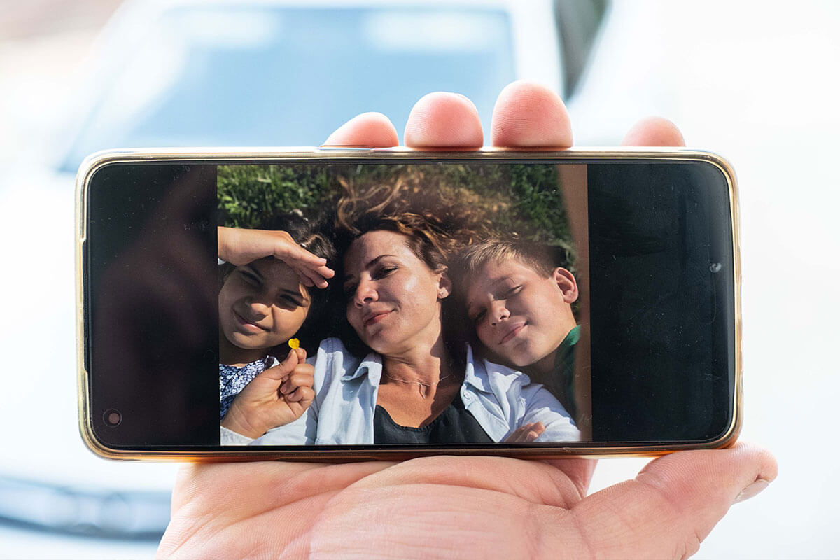 Hand holding mobile phone with image of a woman and two children on it
