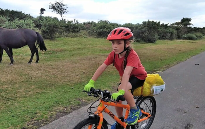 Boy cycling past a pony