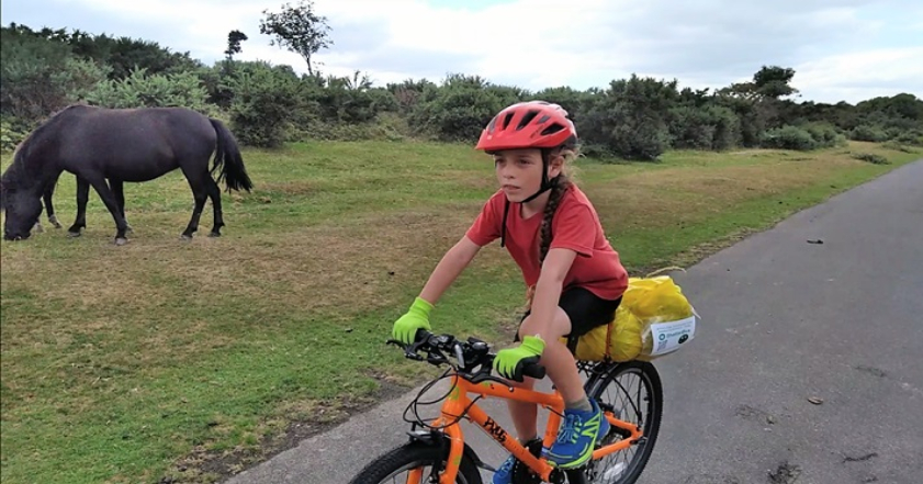 Boy cycling past a pony