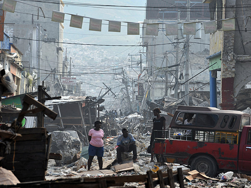 People standing amongst rubble in Haiti after a powerful earthquake in 2010
