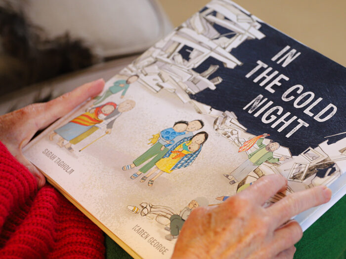 Book titled 'In the Cold Night' with illustrations by Karen George resting on someone's lap