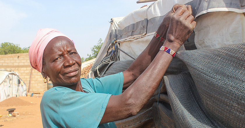 Woman tying up tarpaulins in Burkina Faso