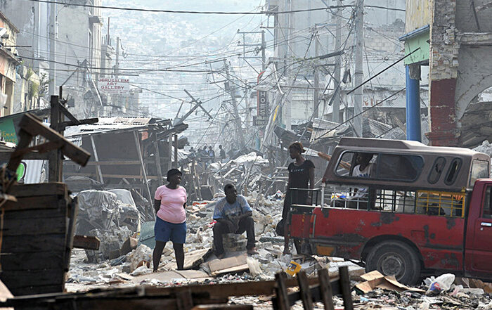 People standing among ruined buildings after the Haiti earthquake in 2010