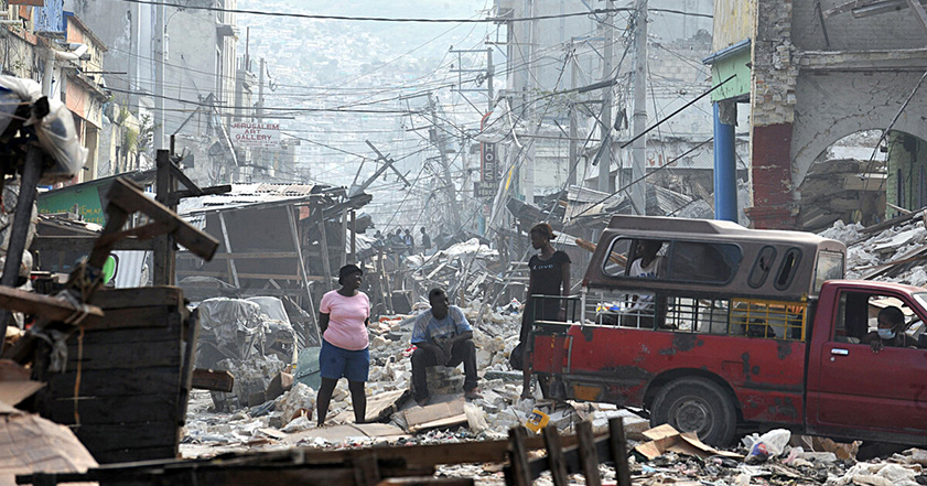 People standing among ruined buildings after the Haiti earthquake in 2010