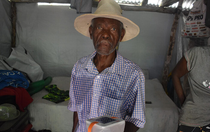 Man wearing hat holding a solar light in Haiti