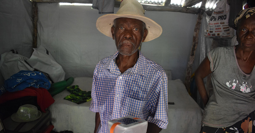 Man wearing hat holding a solar light in Haiti