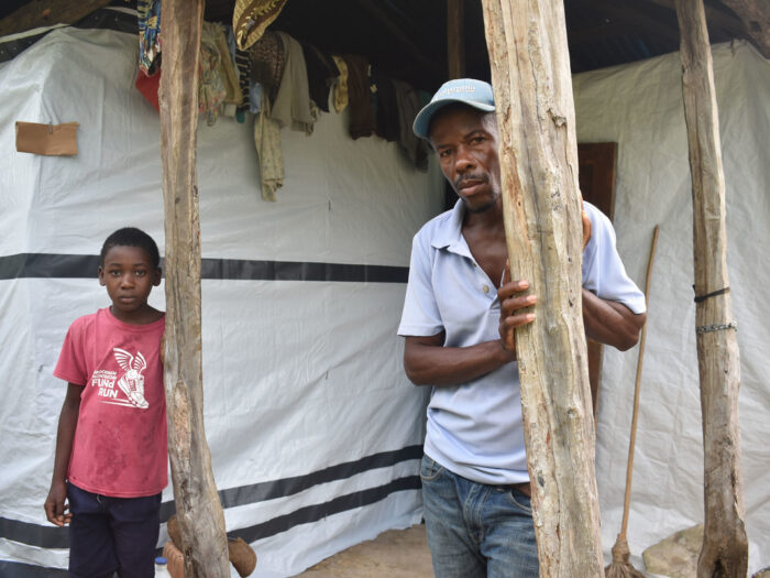 Man and boy standing next to repaired homes in Haiti