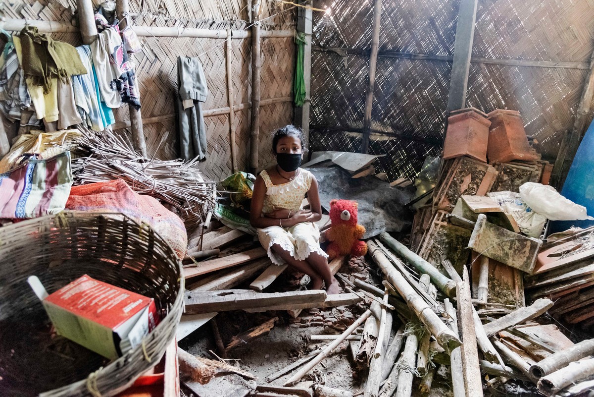 A child sat down by a destroyed home