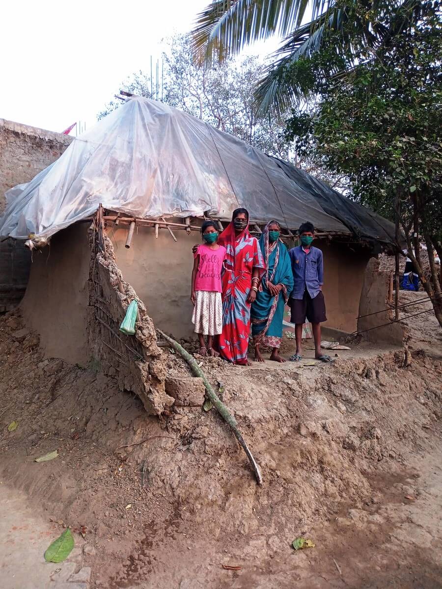 Family stand next to a home destroyed by flooding in India