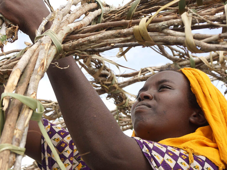 Woman constructing her shelter in Kenya