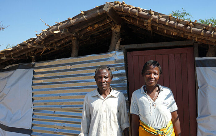Couple standing outside their home in Malawi
