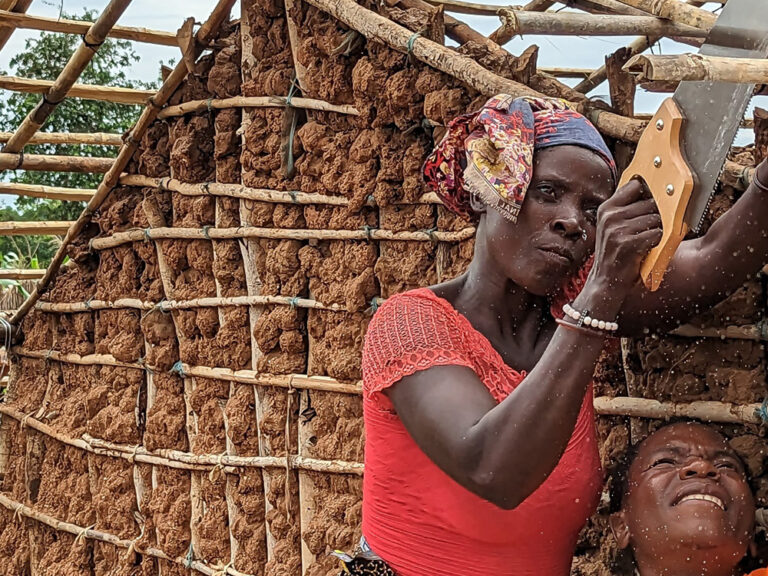 A woman sawing the roof of a new shelter in Mozambique