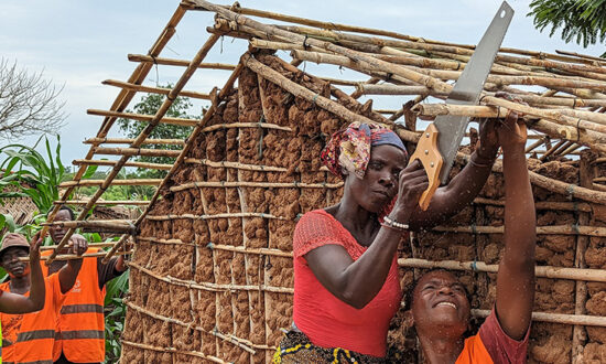 Woman sawing wood on the roof of a new shelter in Mozambique