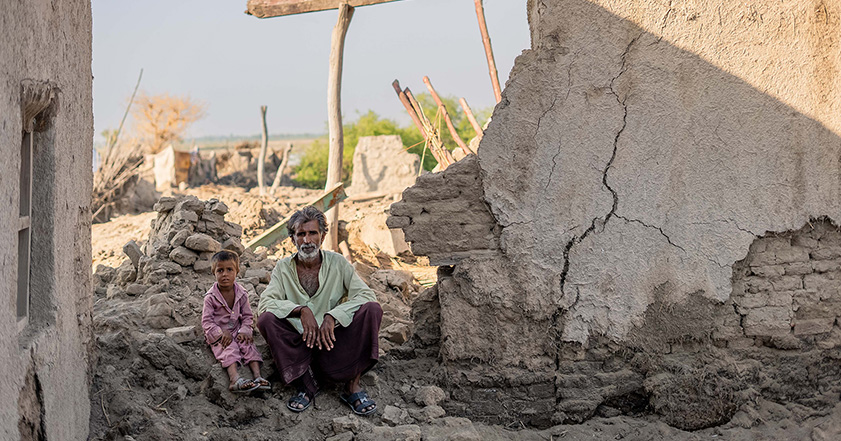 Man and small child sitting in the rubble of a damaged building