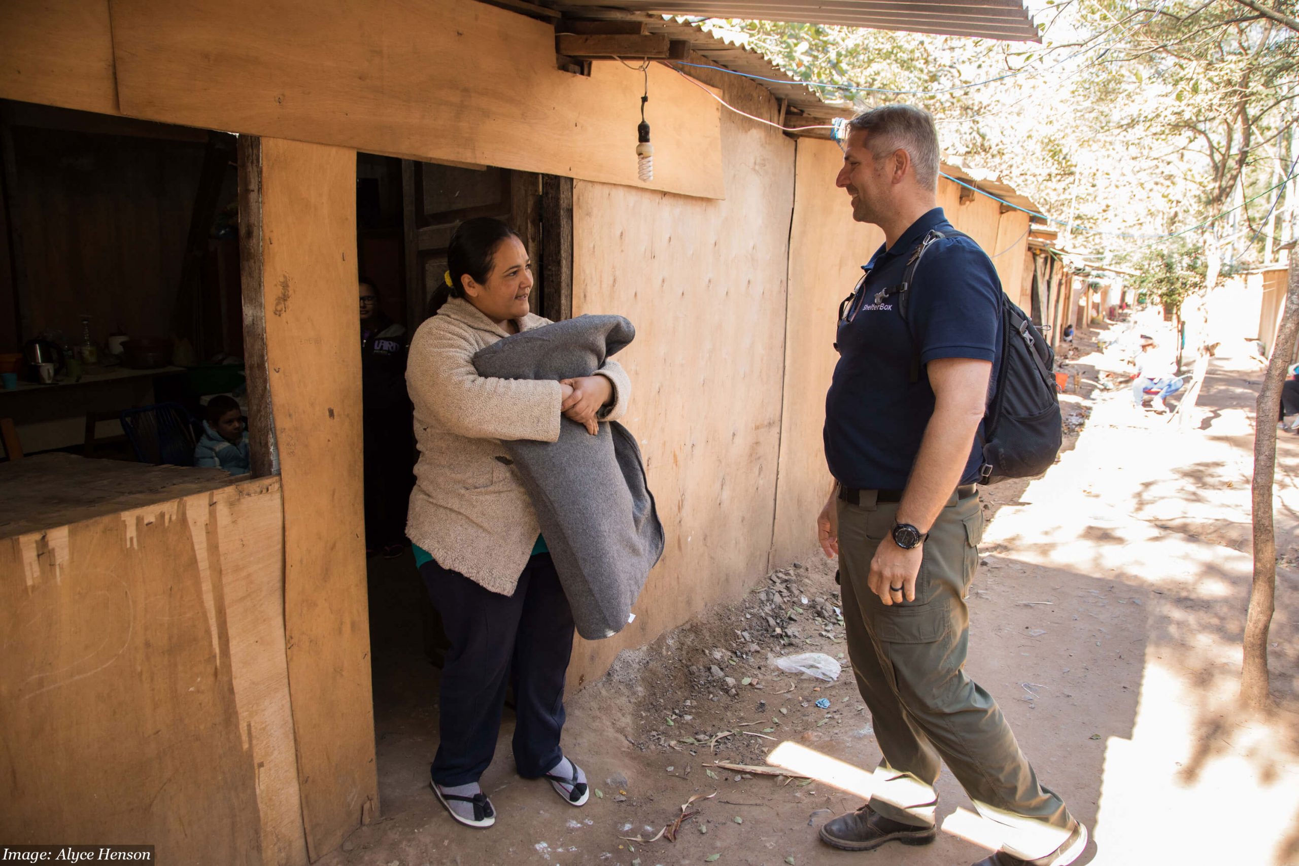 Woman in Paraguay with home made of plywood, talking to a man