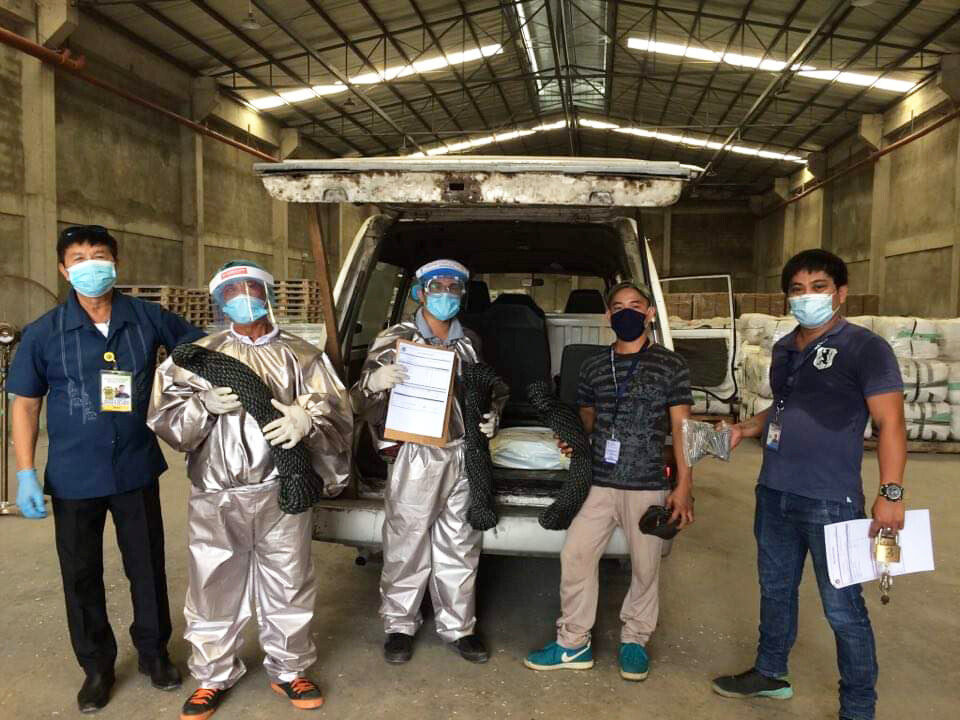 People wearing medical masks and PPE at a warehouse in the Philippines