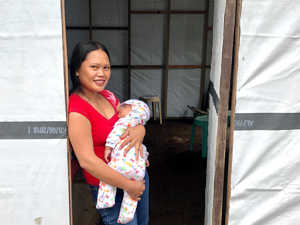 Woman in the Philippines standing at her door with her baby