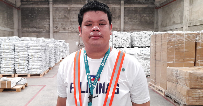 Man standing in from of aid materials inside the ShelterBox Operations Philippines warehouse