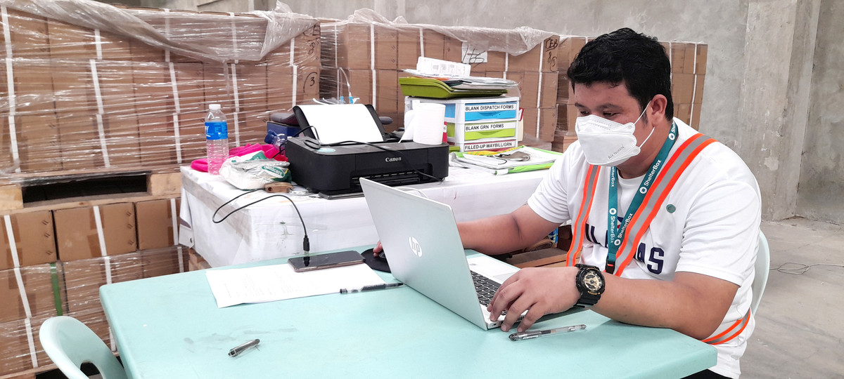 Man wearing a face mask and sat at a desk with a laptop in the ShelterBox Operations Philippines warehouse.
