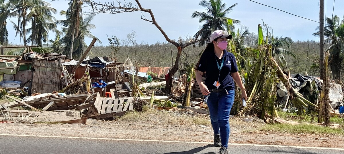 Woman walking next to damaged buildings after Typhoon Rai in the Philippines