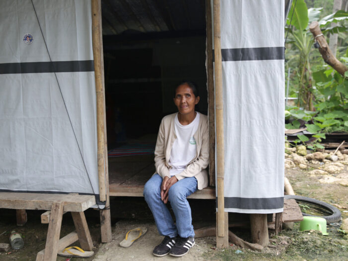 Woman sitting in the door of her shelter after her home was damaged by Super Typhoon Rai in the Philippines