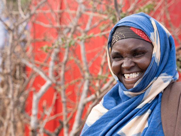 Woman smiling against a red background in Somalia