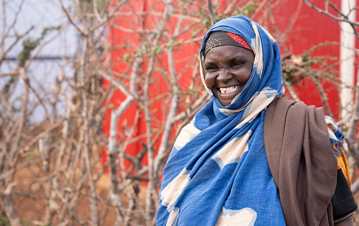 Woman in blue and white head scarf smiling at the camera in Somalia